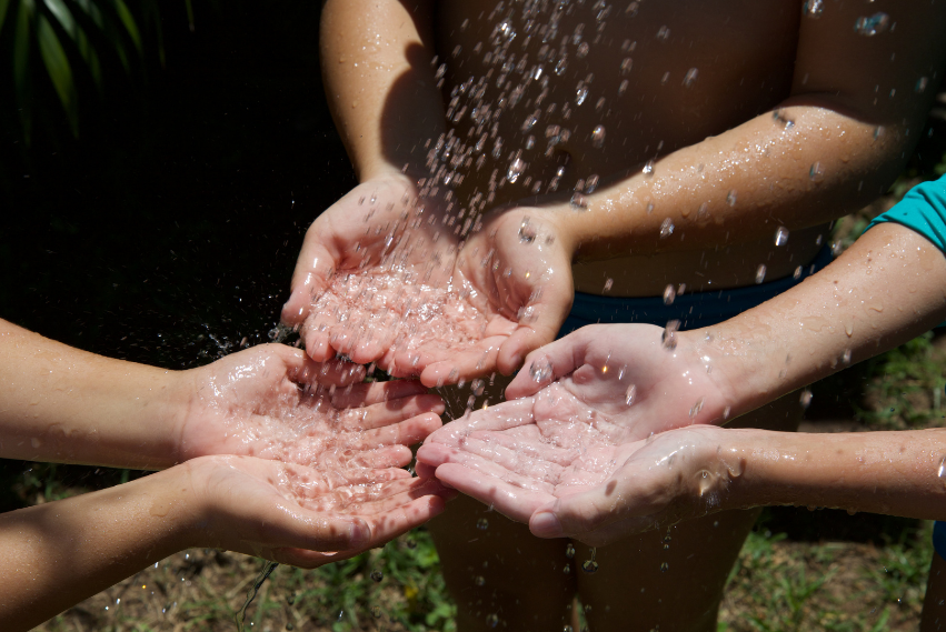 Fotografía de varias manos con chispas de agua cayendo